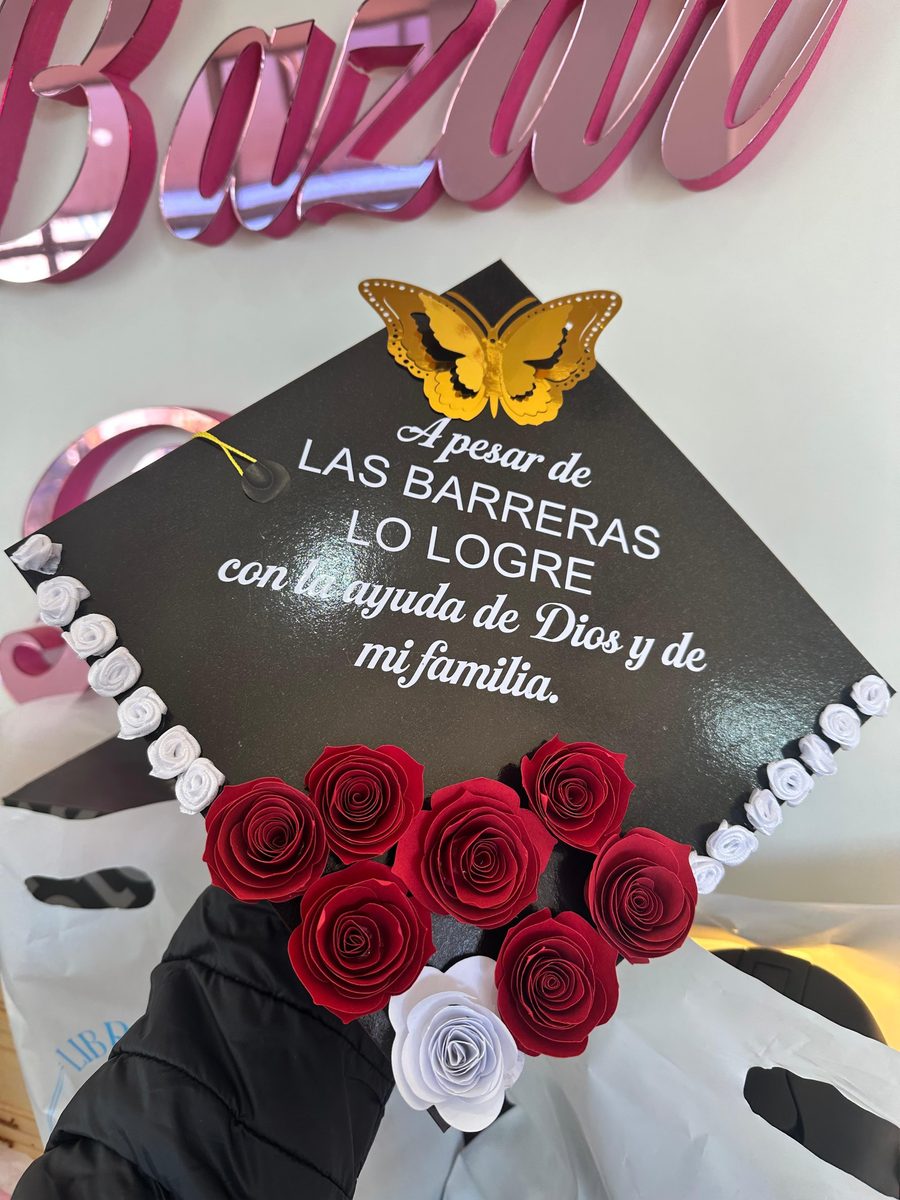 Birrete de graduación negro decorado con rosas rojas y blancas y una mariposa dorada