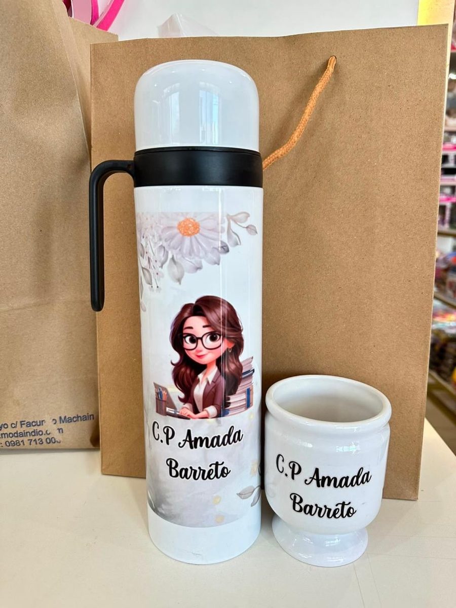 Termo y guampa blancos con un nombre impreso, junto a una bolsa de regalo